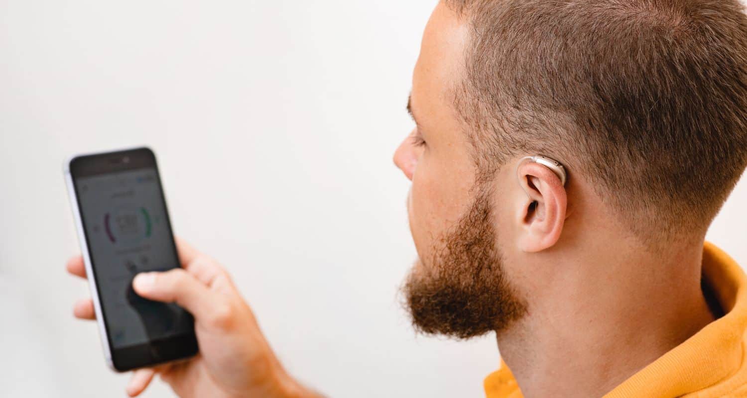 Man with hearing aid adjusting with smart phone