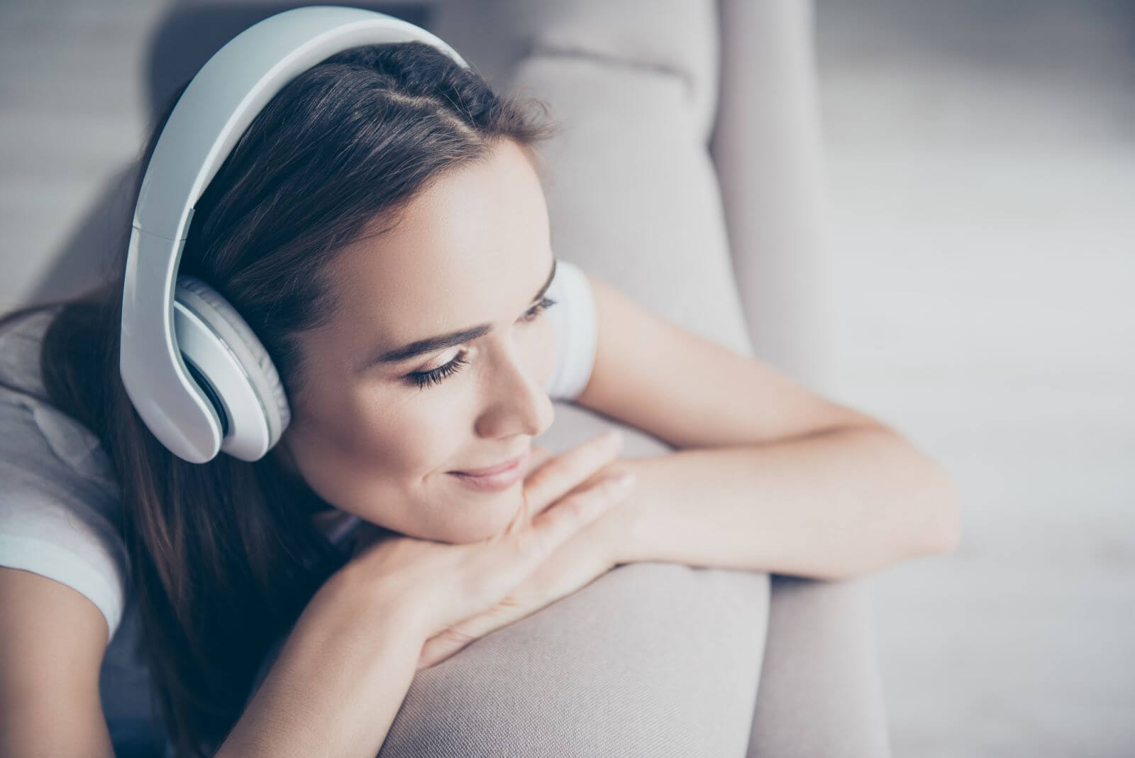 Woman leaning on couch with headphones