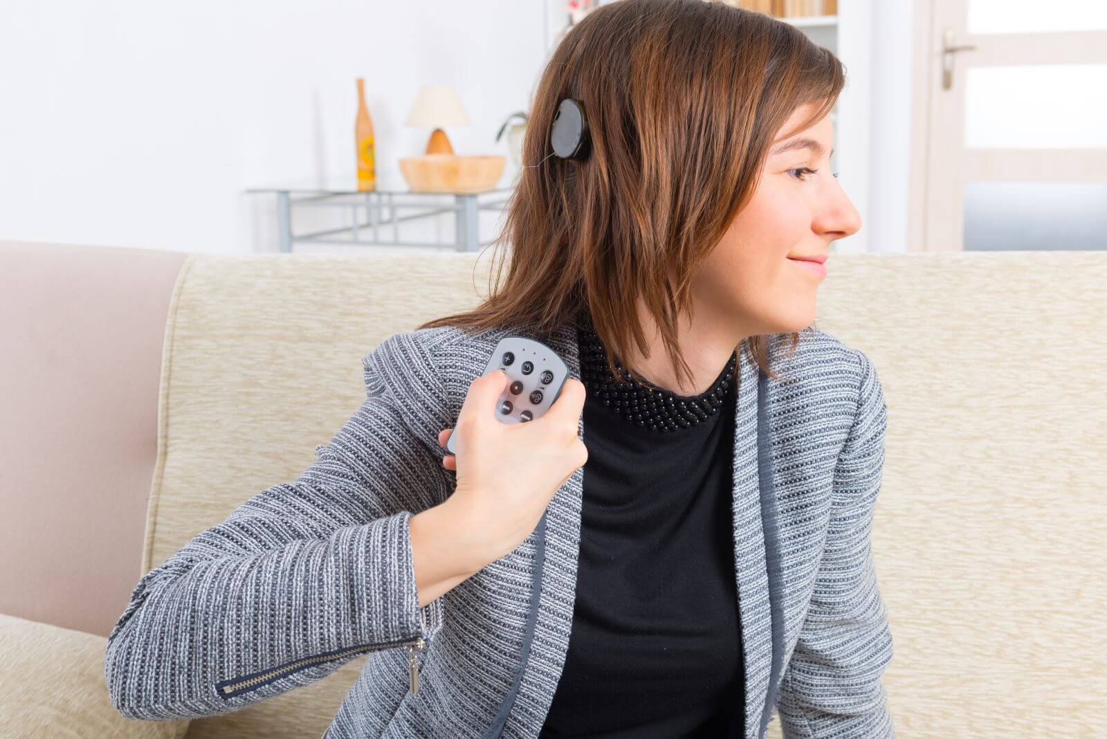 Woman with cochlear implant holding remote control